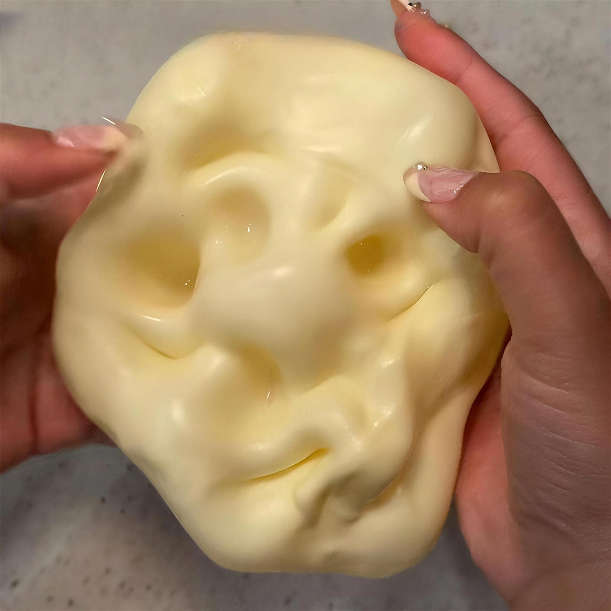 The yellow CHEDDI cheese squishy flattened into a big glossy pancake between two hands