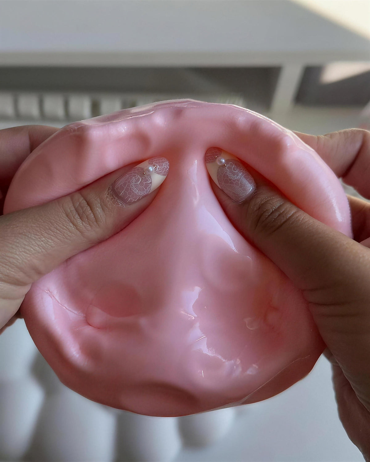 Pink CHEDDI squished flat in two hands in front of a laptop keyboard