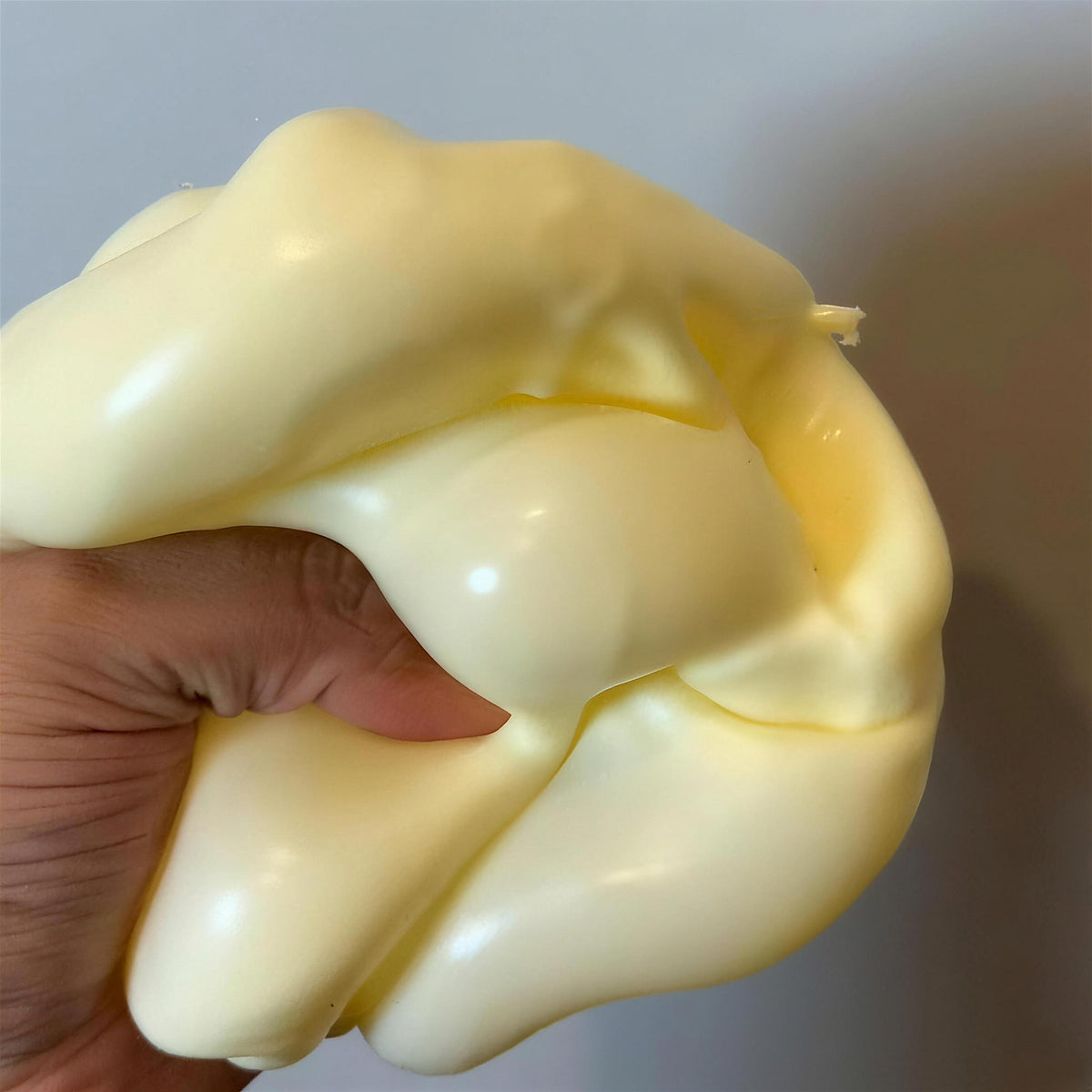 The yellow CHEDDI cheese squishy squeezed into a soft glossy blob in one hand