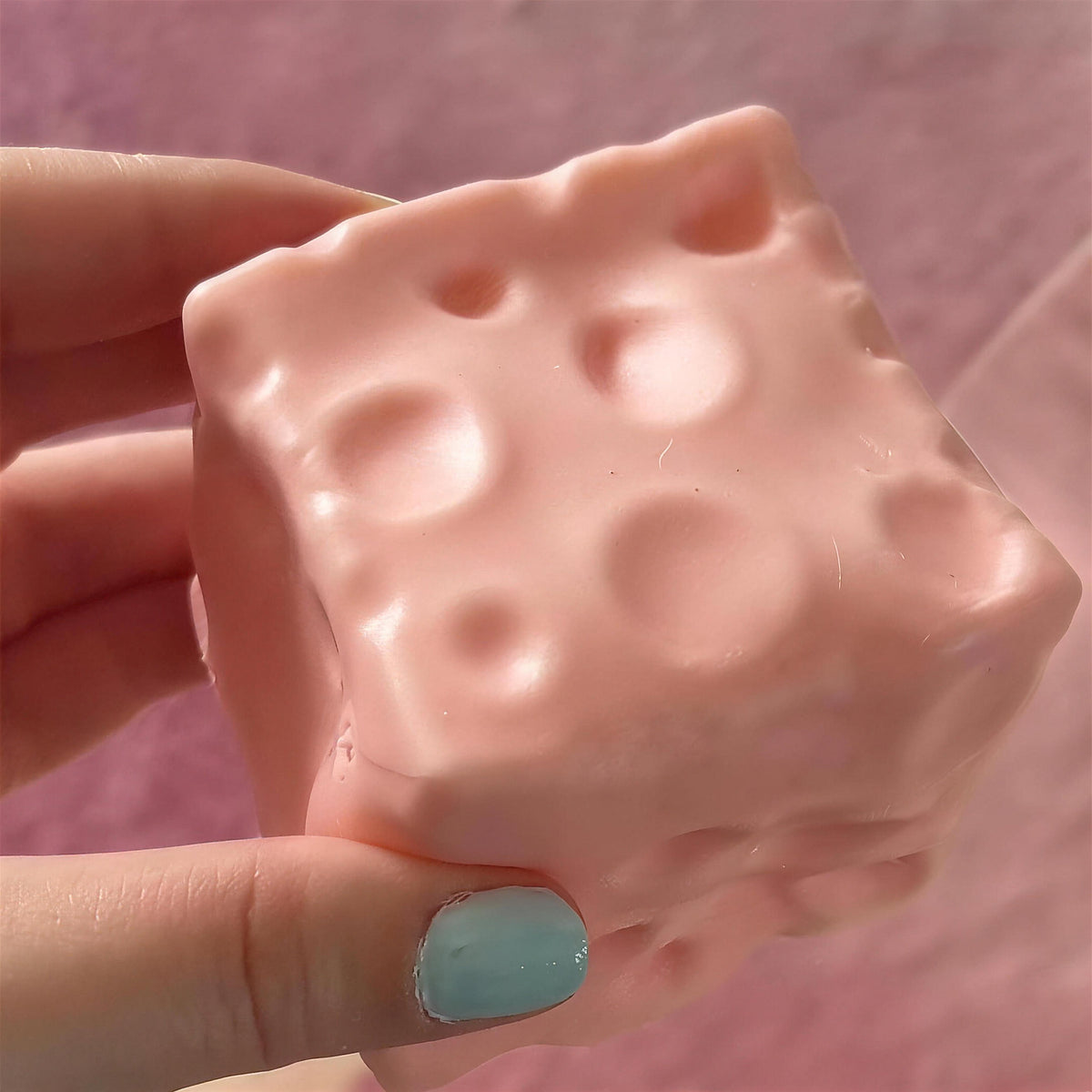 The strawberry pink CHEDDI cheese squishy held in one hand